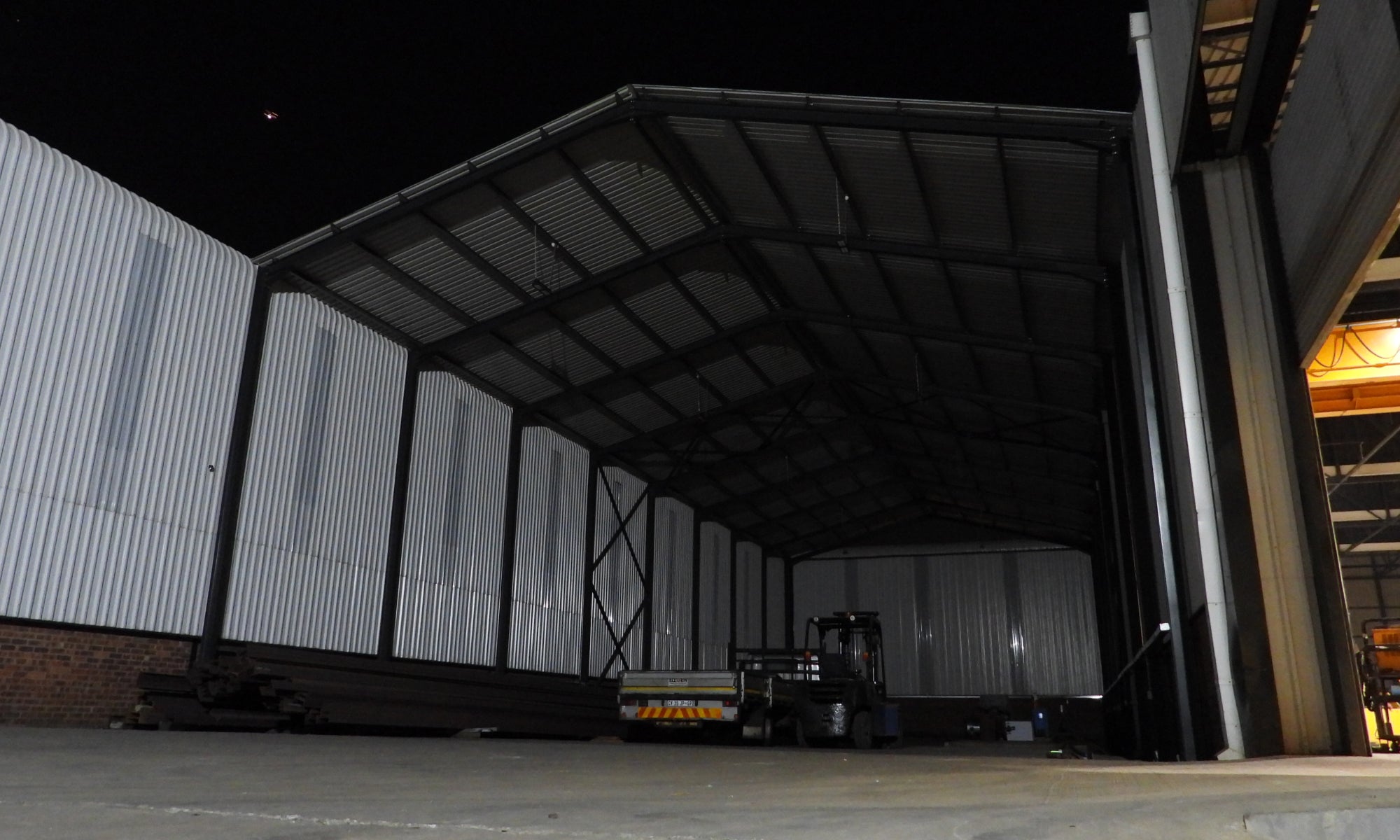 Large industrial warehouse with a forklift at night