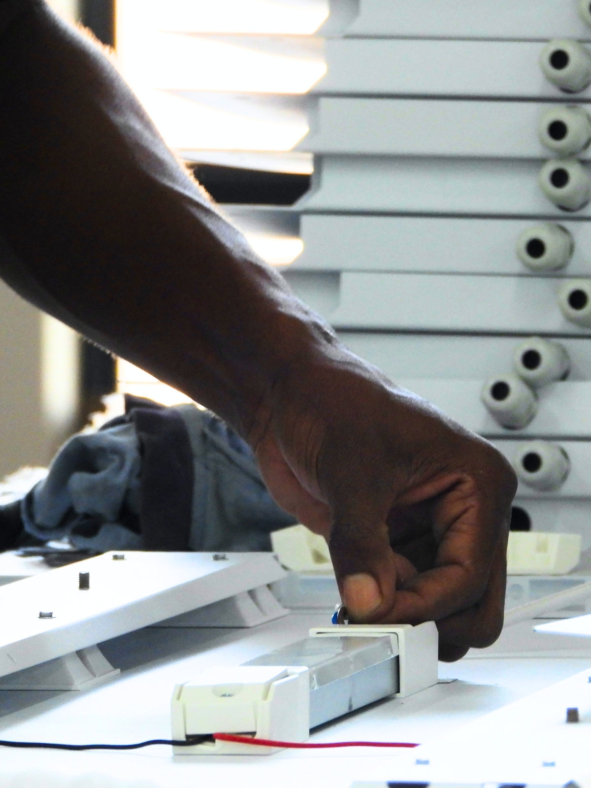 Hand adjusting a white electronic component on a blurred background